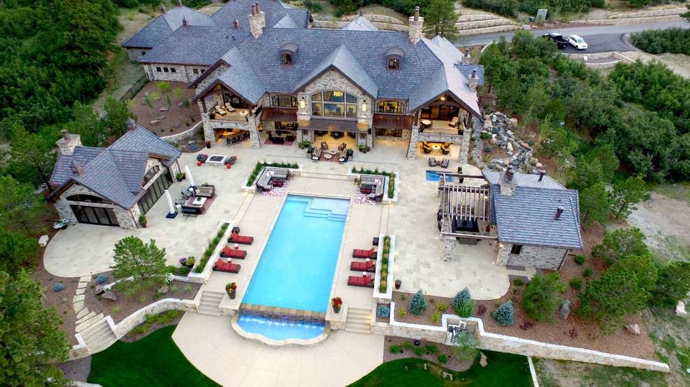 Example of a huge mountain style gray two-story stone house exterior design in Denver with a shingle roof