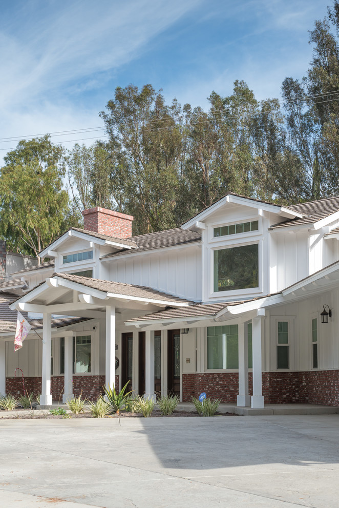 Large cottage red two-story brick house exterior idea in Los Angeles with a clipped gable roof and a shingle roof