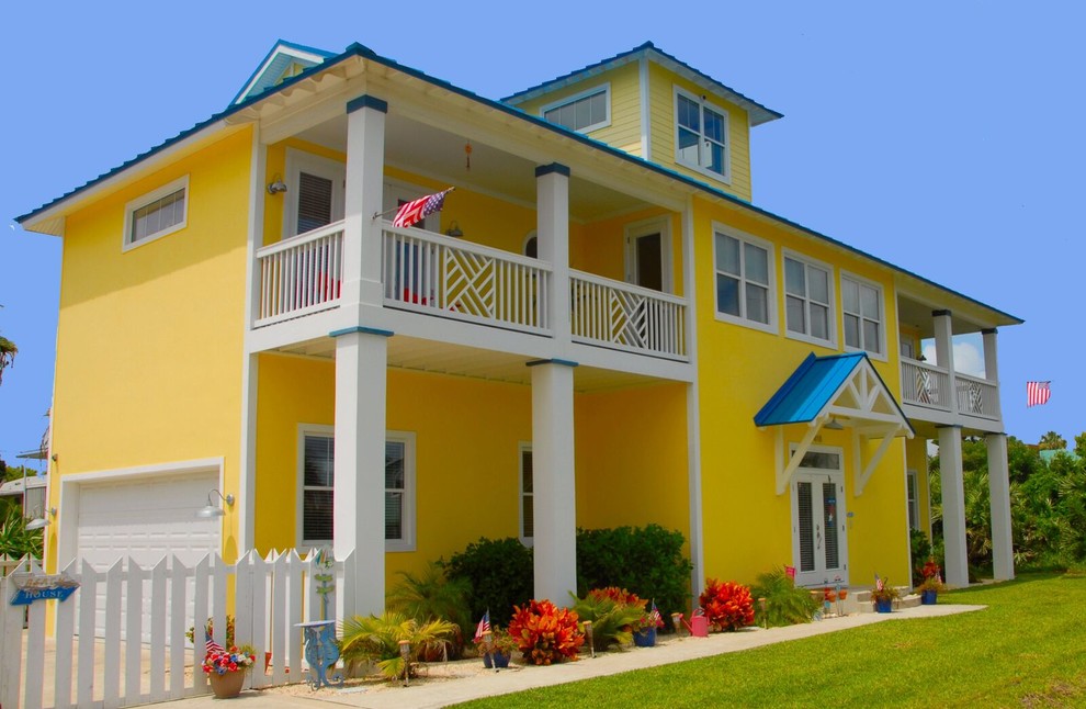 Idée de décoration pour une façade de maison jaune marine en stuc de taille moyenne et à deux étages et plus avec un toit à quatre pans et un toit en shingle.