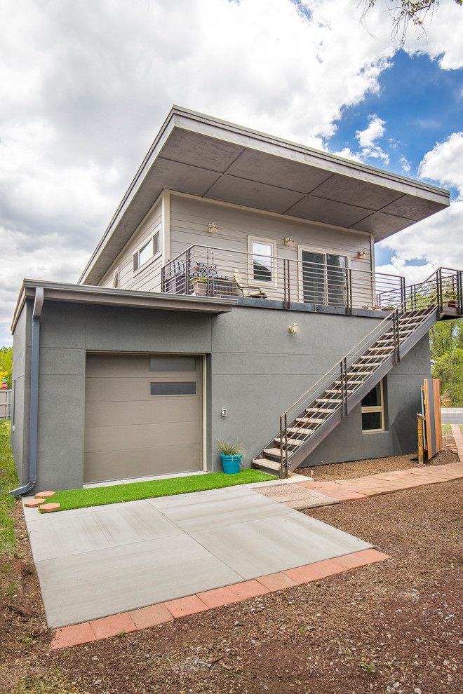 Cette photo montre une petite façade de maison grise moderne à un étage avec un revêtement mixte, un toit en appentis et un toit en métal.