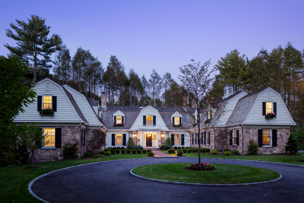 Large elegant white two-story stone exterior home photo in Boston with a gambrel roof