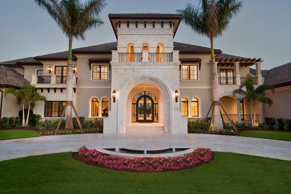 Photo of an expansive and beige mediterranean two floor render detached house in Miami with a hip roof and a tiled roof.