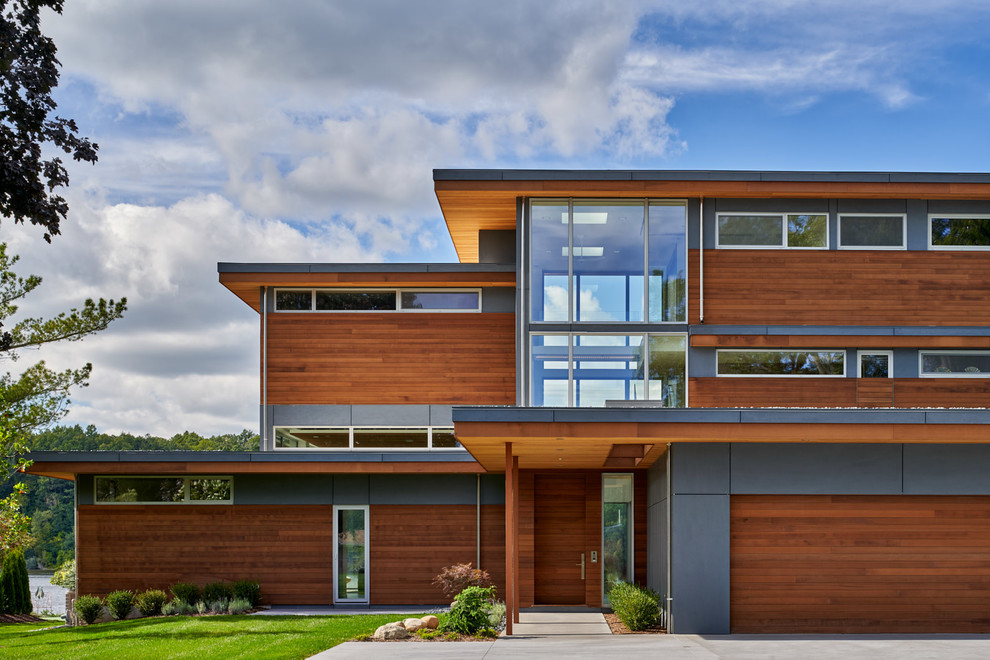 Ejemplo de fachada de casa multicolor actual de tres plantas con revestimientos combinados y tejado plano