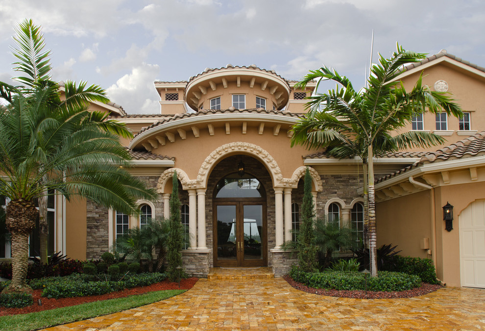 Cette image montre une très grande façade de maison beige méditerranéenne à deux étages et plus avec un revêtement mixte.