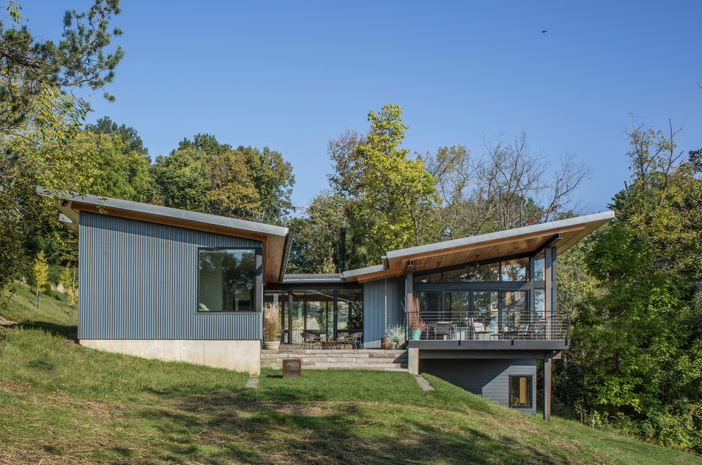 Diseño de fachada de casa azul contemporánea de tamaño medio de dos plantas con revestimiento de metal, tejado plano y tejado de metal