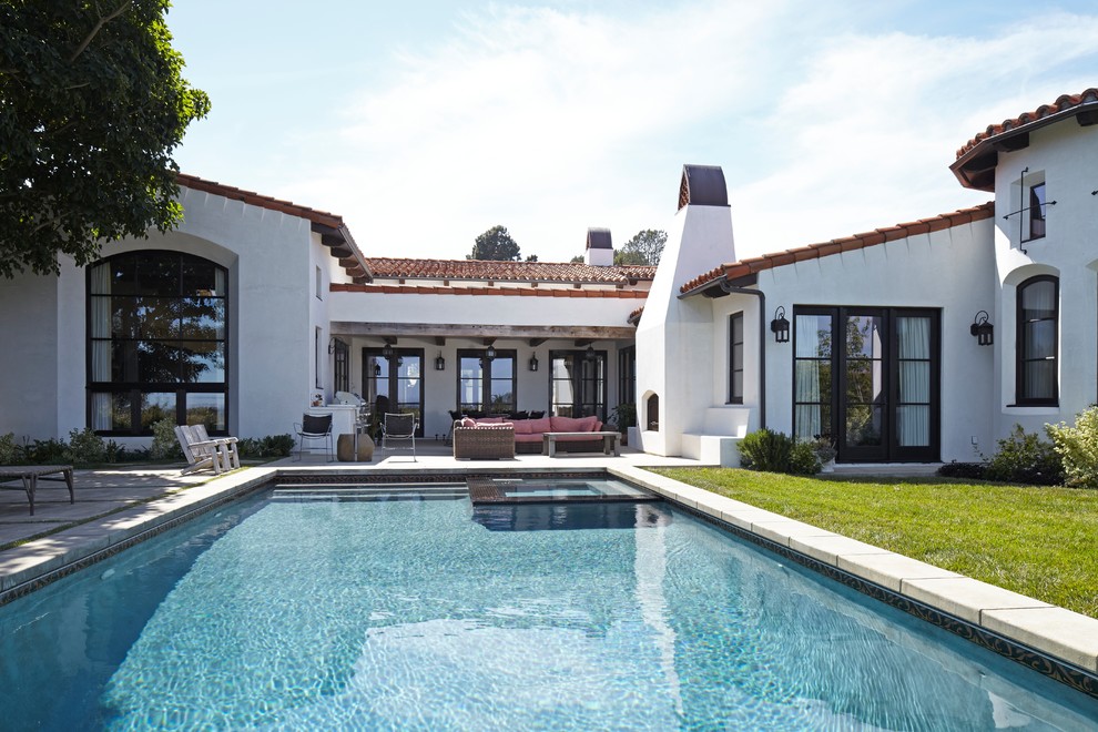 Example of a mid-sized tuscan white one-story stucco exterior home design in Los Angeles with a tile roof