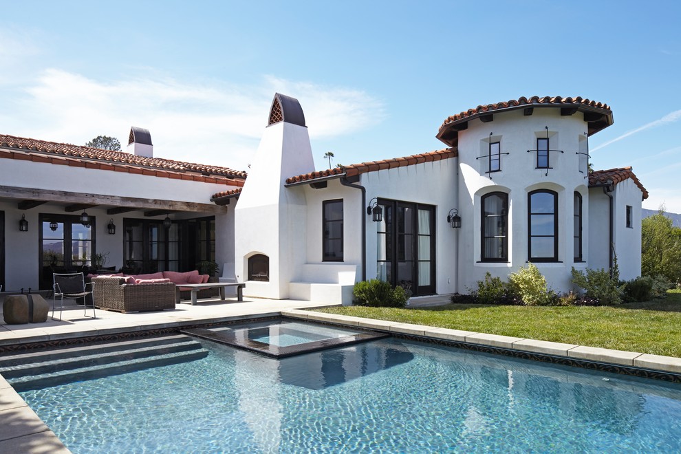 Стильный дизайн: одноэтажный, белый частный загородный дом среднего размера в средиземноморском стиле с облицовкой из цементной штукатурки, двускатной крышей и черепичной крышей - последний тренд
