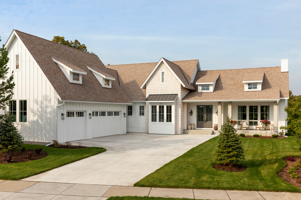 Réalisation d'une façade de maison blanche champêtre en planches et couvre-joints à un étage avec un toit à deux pans, un toit en shingle et un toit marron.