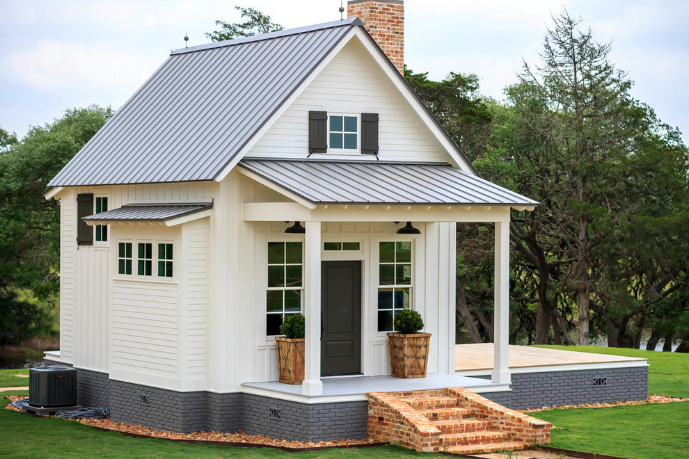 Mittelgroßes, Zweistöckiges Landhaus Einfamilienhaus mit Vinylfassade, weißer Fassadenfarbe, Satteldach und Blechdach in Austin