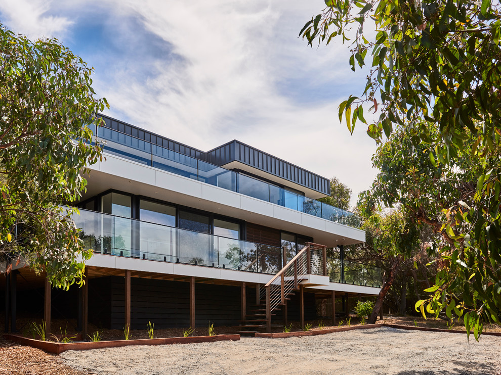Ejemplo de fachada de casa negra minimalista de tamaño medio de dos plantas con revestimiento de metal, tejado plano y tejado de metal
