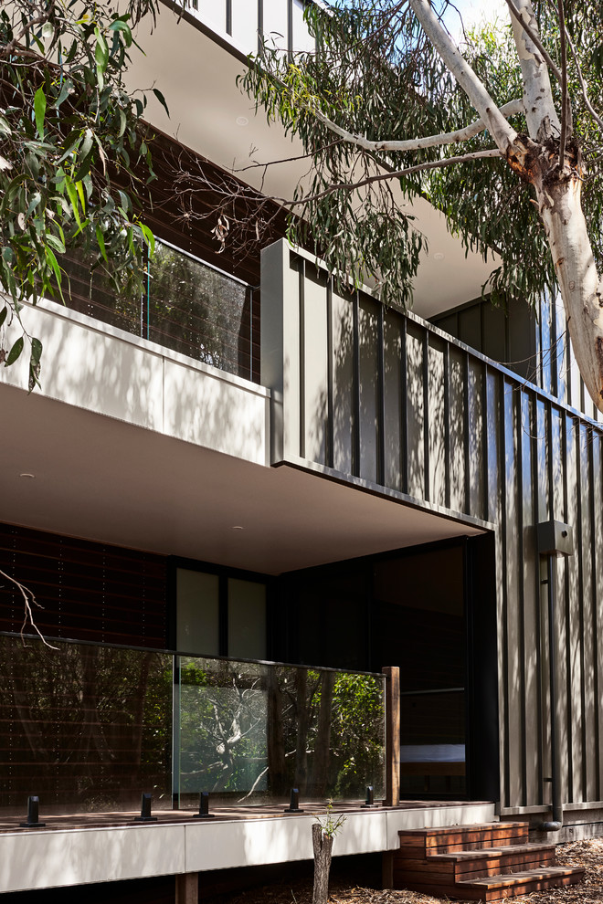 Imagen de fachada de casa negra moderna de tamaño medio de dos plantas con revestimiento de metal, tejado plano y tejado de metal