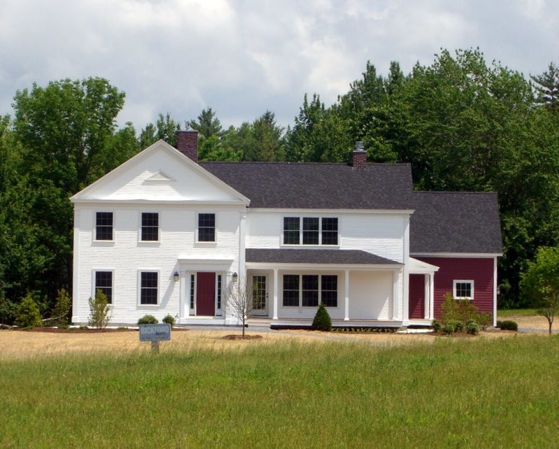 На фото: двухэтажный, белый дом в стиле кантри с облицовкой из винила и двускатной крышей с
