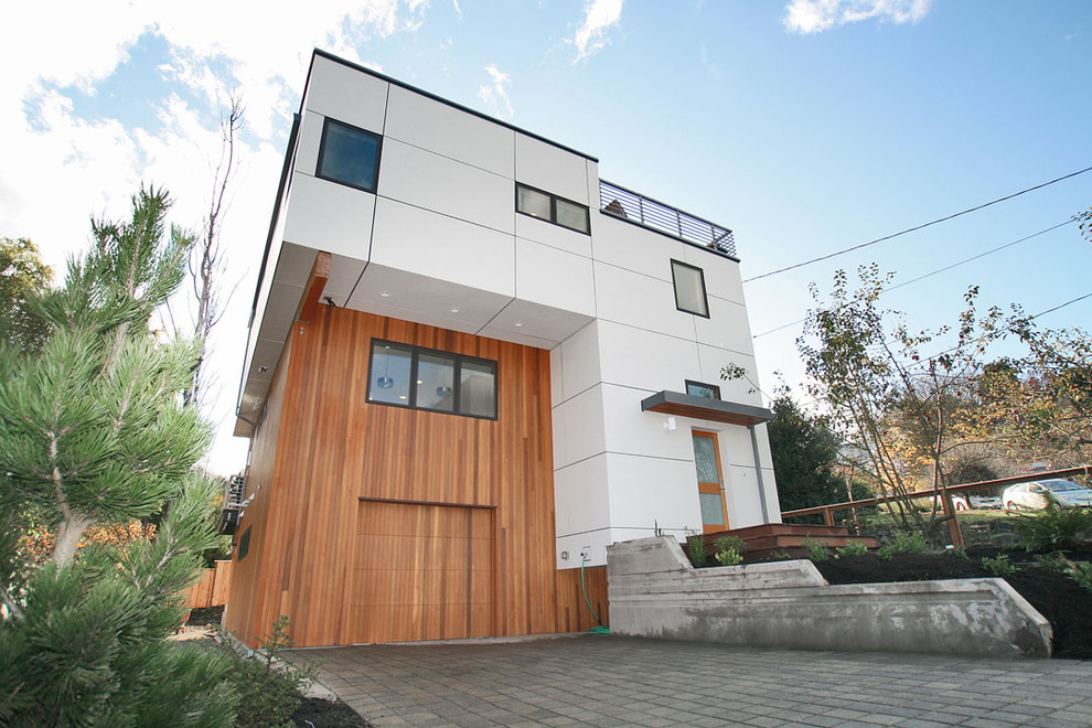 Medium sized and gey contemporary house exterior in Seattle with three floors, mixed cladding and a flat roof.