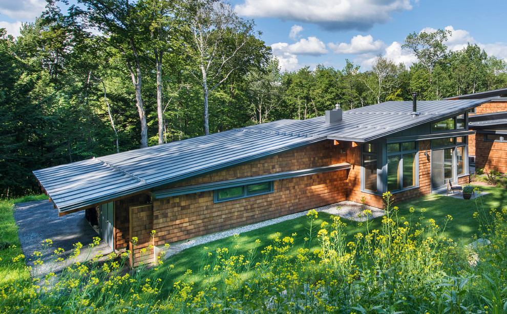 Cette image montre une petite façade de maison marron design en bois de plain-pied avec un toit en appentis.