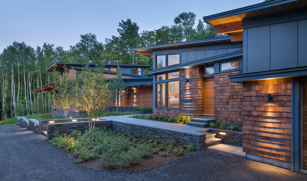 Cette image montre une façade de maison marron design en bois de taille moyenne et à un étage avec un toit en appentis.