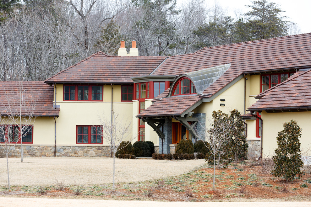 Diseño de fachada de casa beige de estilo americano grande de dos plantas con revestimiento de estuco, tejado a cuatro aguas y tejado de teja de madera