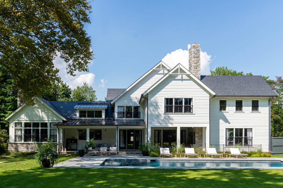 Imagen de fachada de casa blanca campestre grande de dos plantas con tejado a dos aguas, tejado de teja de madera y revestimientos combinados