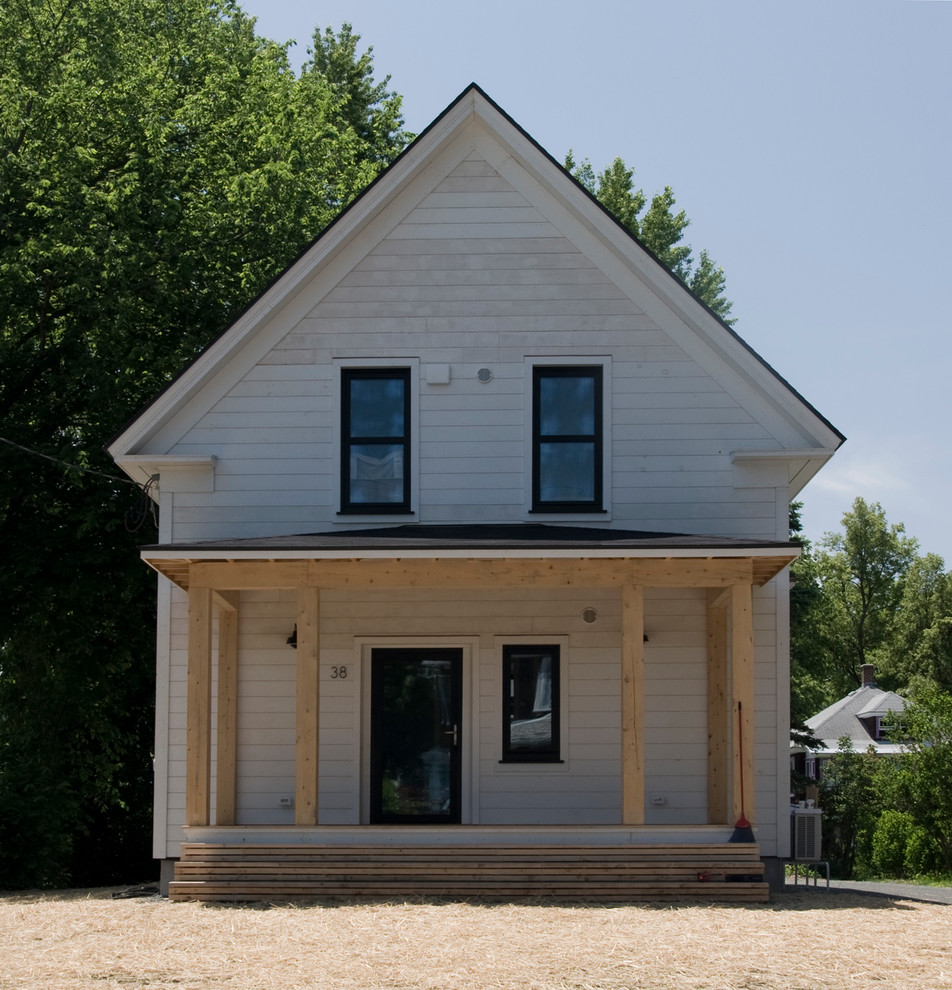 Esempio della facciata di una casa piccola bianca country a due piani con rivestimento in legno e tetto a capanna