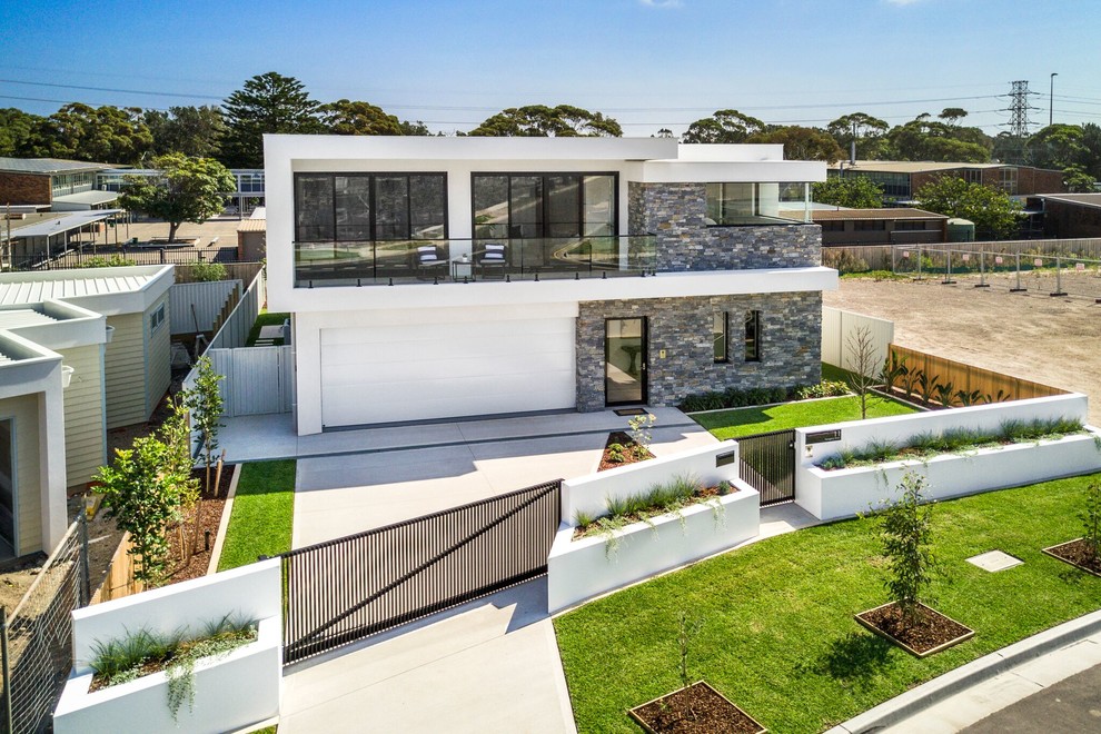 Immagine della villa bianca contemporanea a due piani con rivestimento in mattoni, tetto piano e copertura in metallo o lamiera
