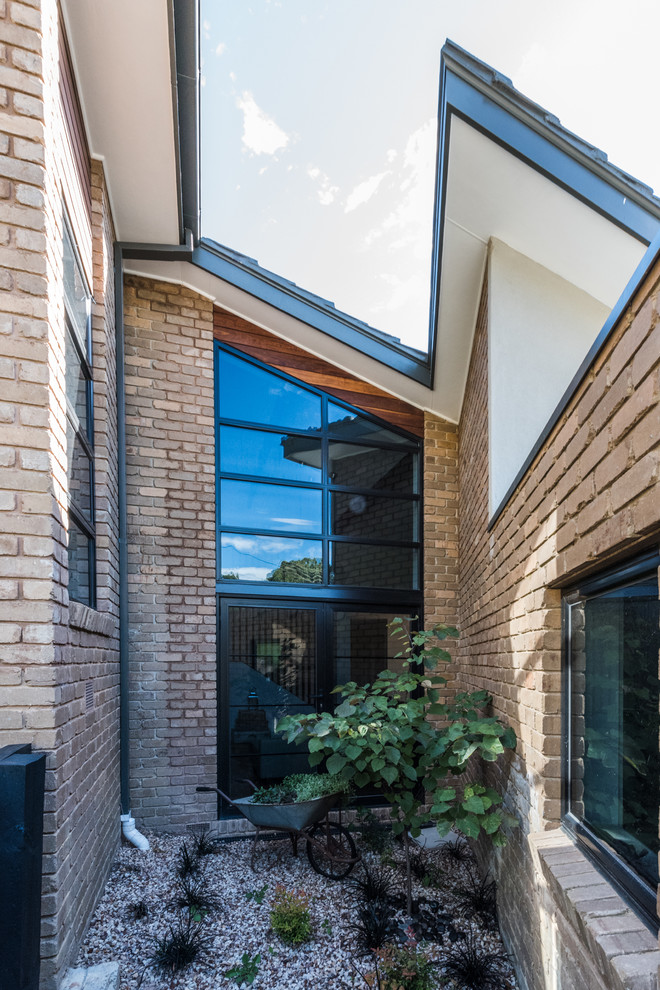 Inspiration pour une grande façade de maison marron minimaliste en brique à un étage avec un toit à deux pans.