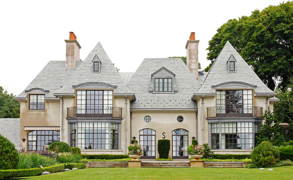 Inspiration pour une très grande façade de maison beige traditionnelle à deux étages et plus avec un toit à quatre pans.