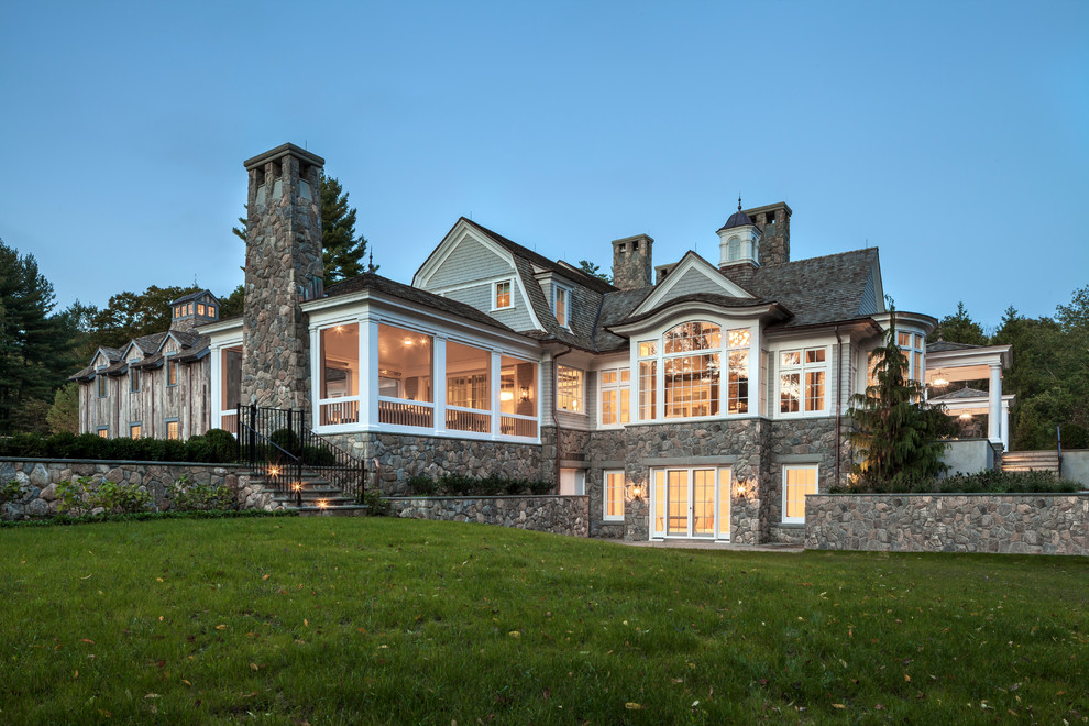 Large traditional beige two-story wood house exterior idea with a gambrel roof and a shingle roof
