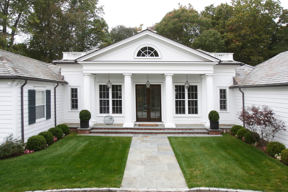 Inspiration for an expansive and white traditional bungalow house exterior in New York with wood cladding.