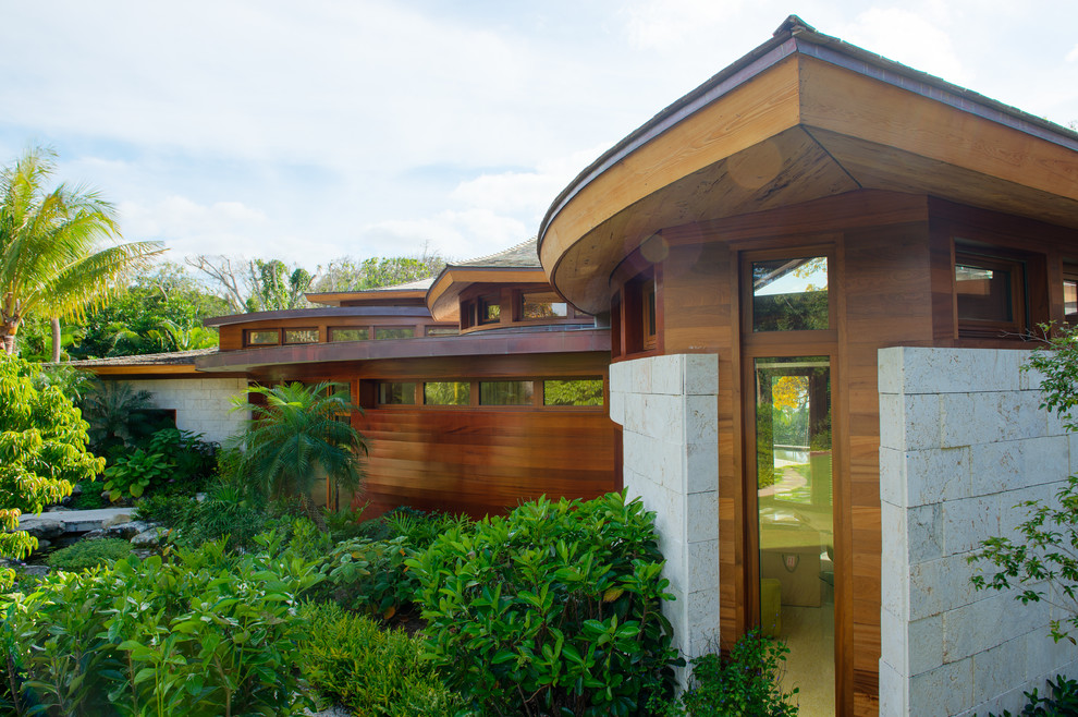 Foto de fachada de casa marrón tropical a niveles con revestimientos combinados y tejado a cuatro aguas