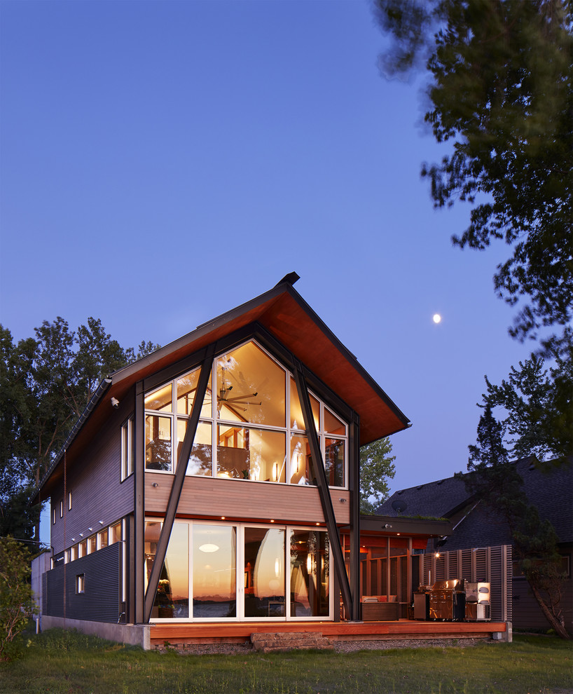 Foto della villa piccola marrone contemporanea a due piani con rivestimento in legno, tetto a capanna e copertura verde