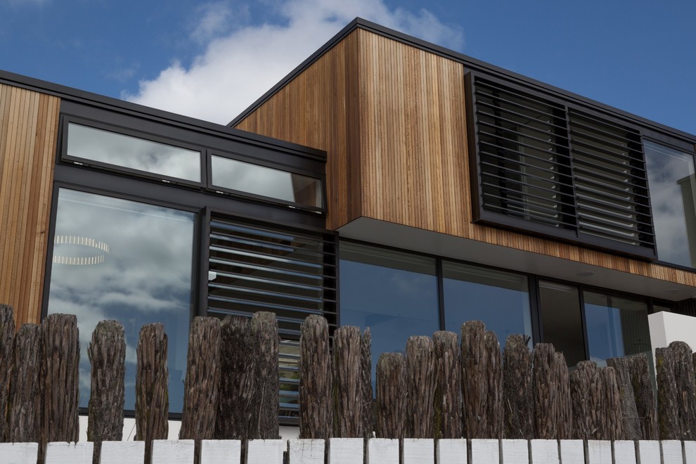 Réalisation d'une grande façade de maison noire design en bois à deux étages et plus avec un toit plat.