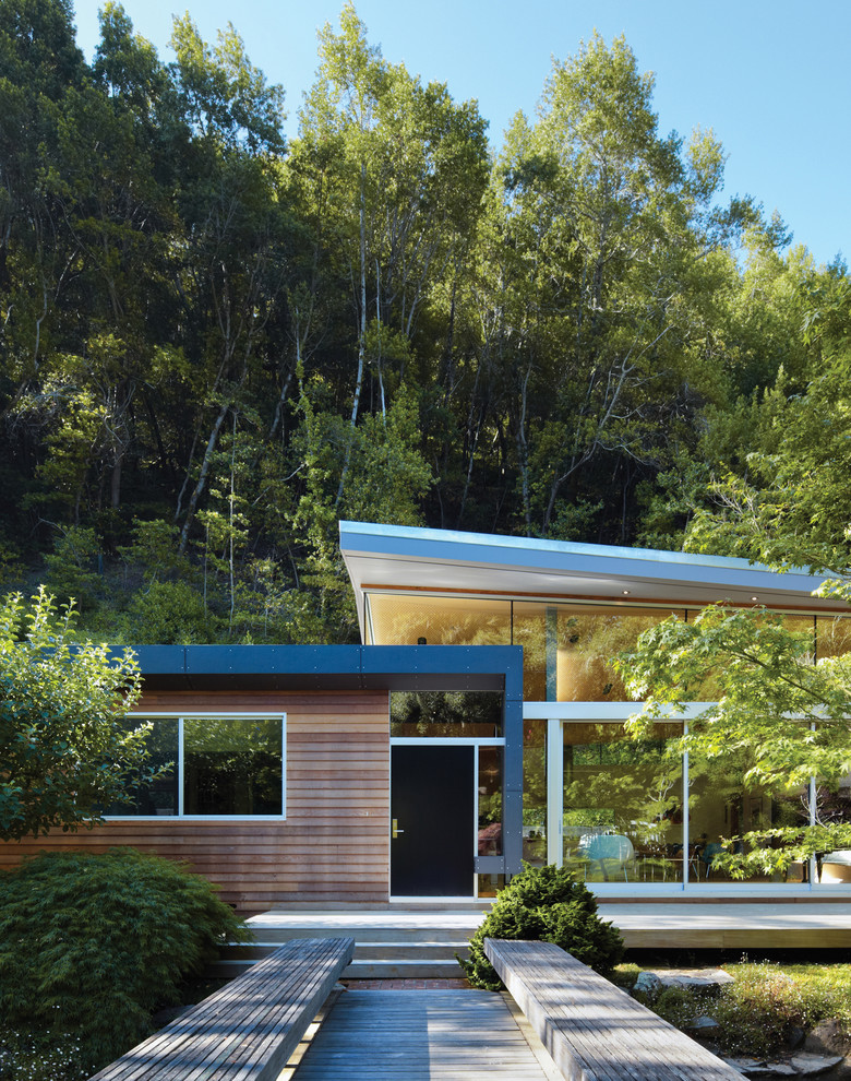 Medium sized and brown midcentury bungalow house exterior in San Francisco with a lean-to roof and wood cladding.