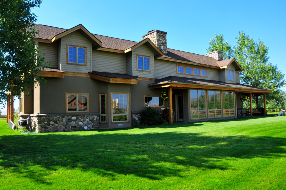 Immagine della facciata di una casa grande beige country a due piani con rivestimento in stucco