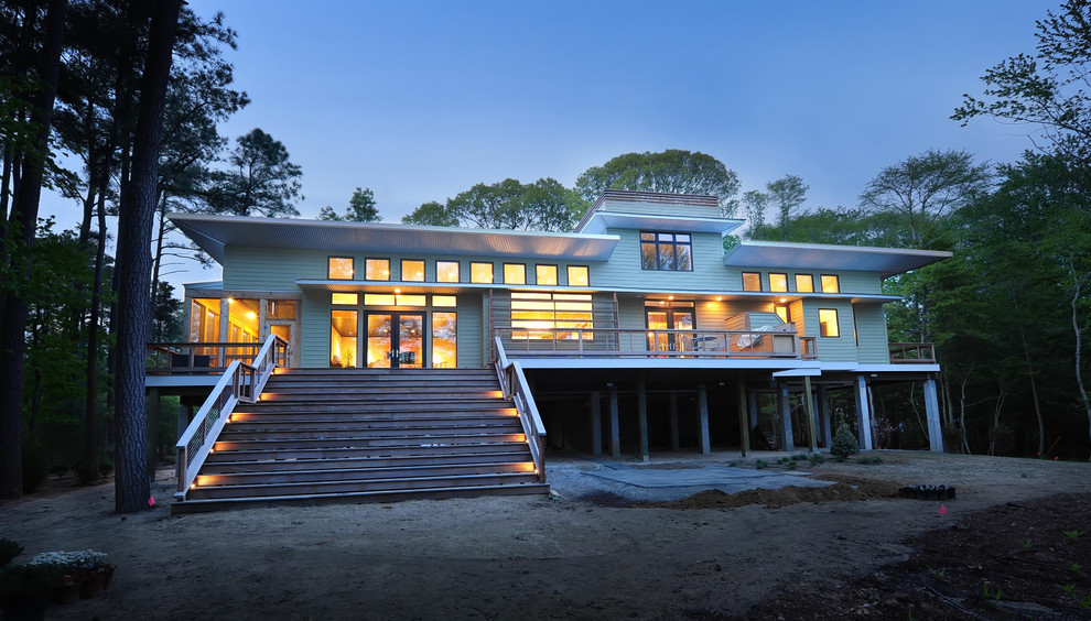 Aménagement d'une grande façade de maison verte contemporaine en panneau de béton fibré à un étage avec un toit plat et un toit en métal.