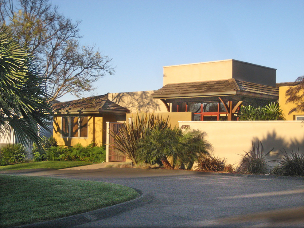 На фото: одноэтажный, бежевый дом среднего размера в современном стиле с облицовкой из цементной штукатурки и плоской крышей с