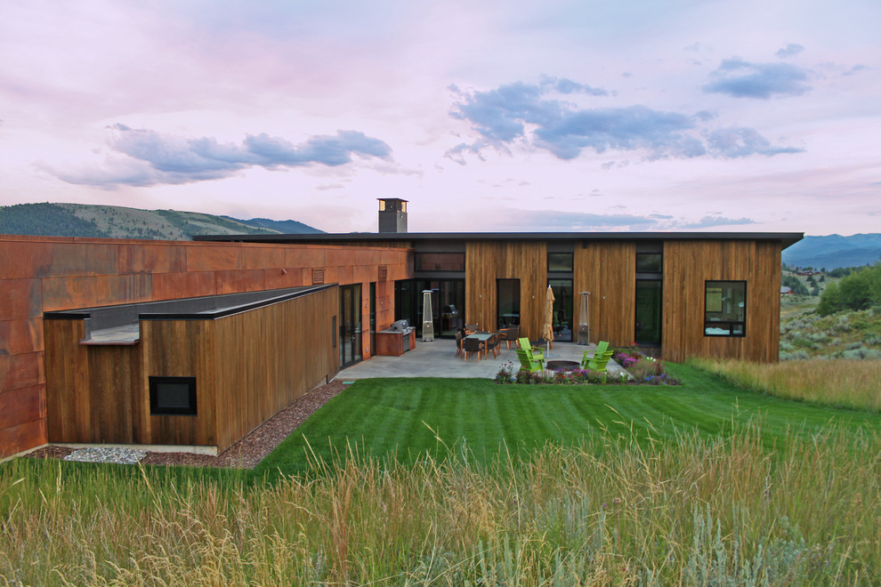 Идея дизайна: большой, двухэтажный, коричневый частный загородный дом в современном стиле с комбинированной облицовкой, плоской крышей и металлической крышей