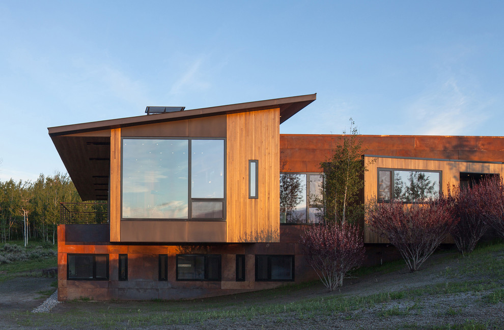 Imagen de fachada de casa marrón actual grande de dos plantas con revestimientos combinados, tejado plano y tejado de metal