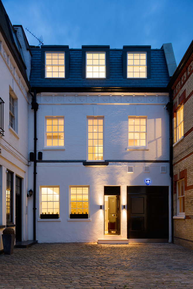 Large and white classic brick terraced house in London with three floors and a tiled roof.