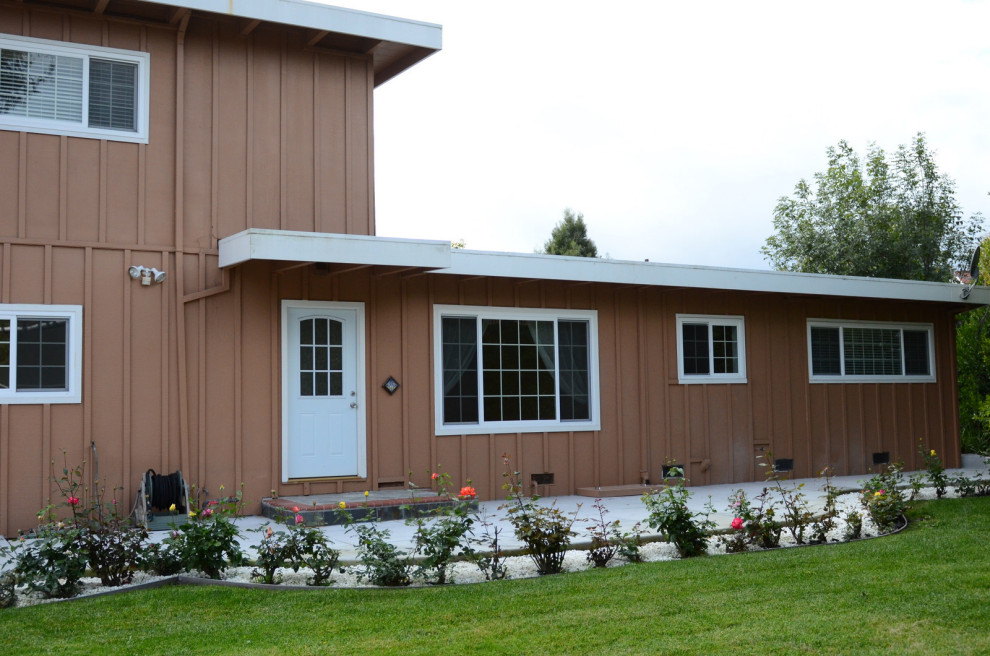 Cette photo montre une façade de maison blanche moderne en bois de taille moyenne et à un étage avec un toit plat.