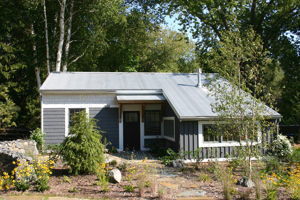Diseño de fachada de casa gris costera pequeña de una planta con revestimiento de madera, tejado a dos aguas y tejado de metal