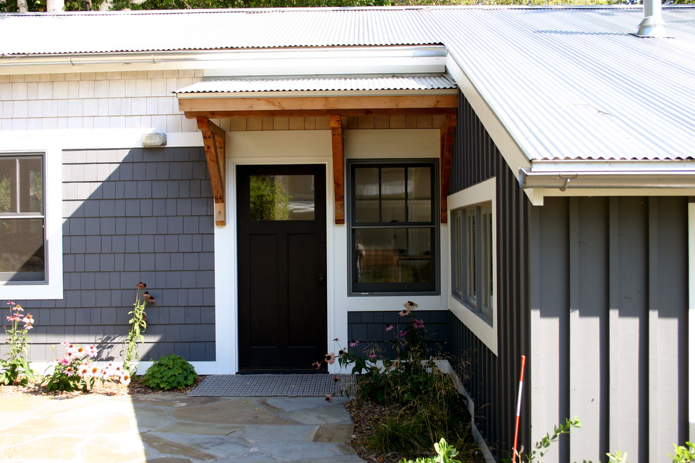 Ejemplo de fachada de casa gris marinera pequeña de una planta con revestimiento de madera, tejado a dos aguas y tejado de metal