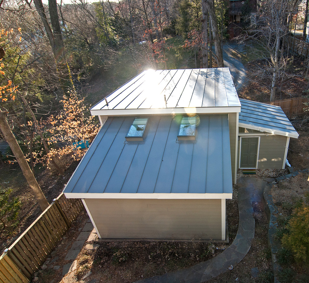 На фото: маленький, одноэтажный, серый частный загородный дом в классическом стиле с облицовкой из ЦСП, односкатной крышей и металлической крышей для на участке и в саду с