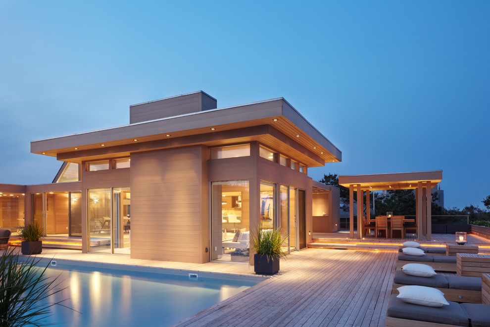 Aménagement d'une grande façade de maison beige bord de mer en bois de plain-pied avec un toit plat.