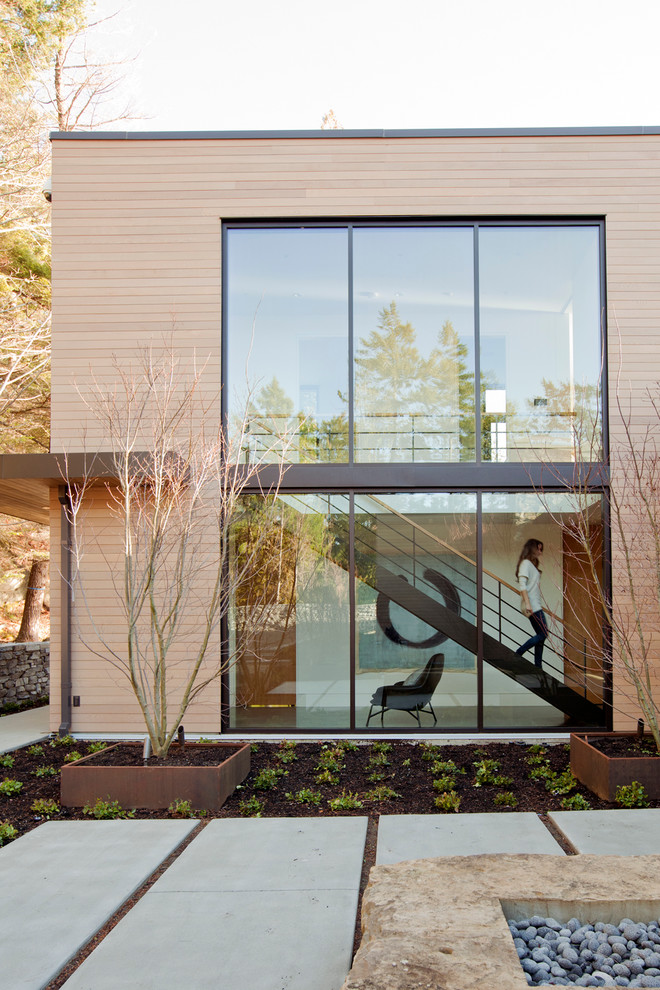 Modelo de fachada de casa beige contemporánea de dos plantas con revestimiento de madera y tejado plano