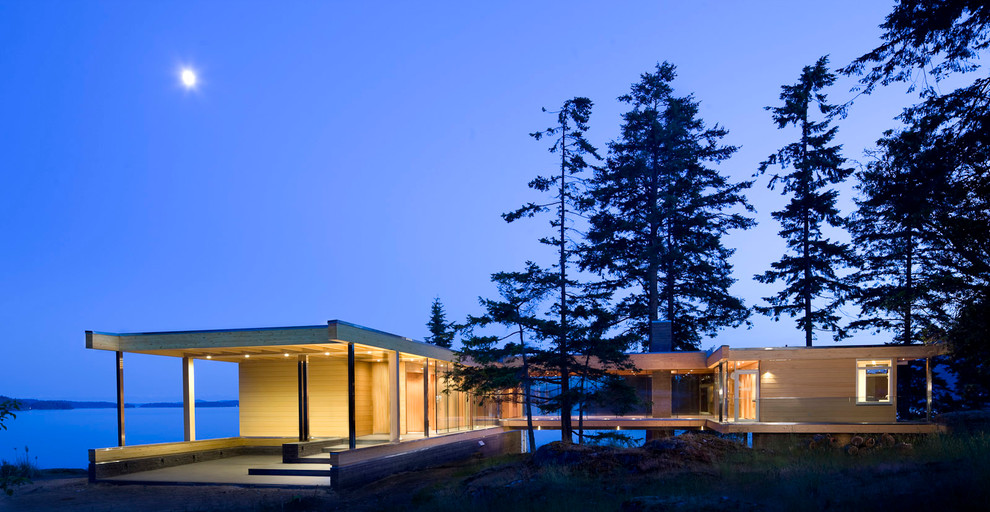 This is an example of a large and brown modern bungalow detached house in Vancouver with wood cladding and a flat roof.