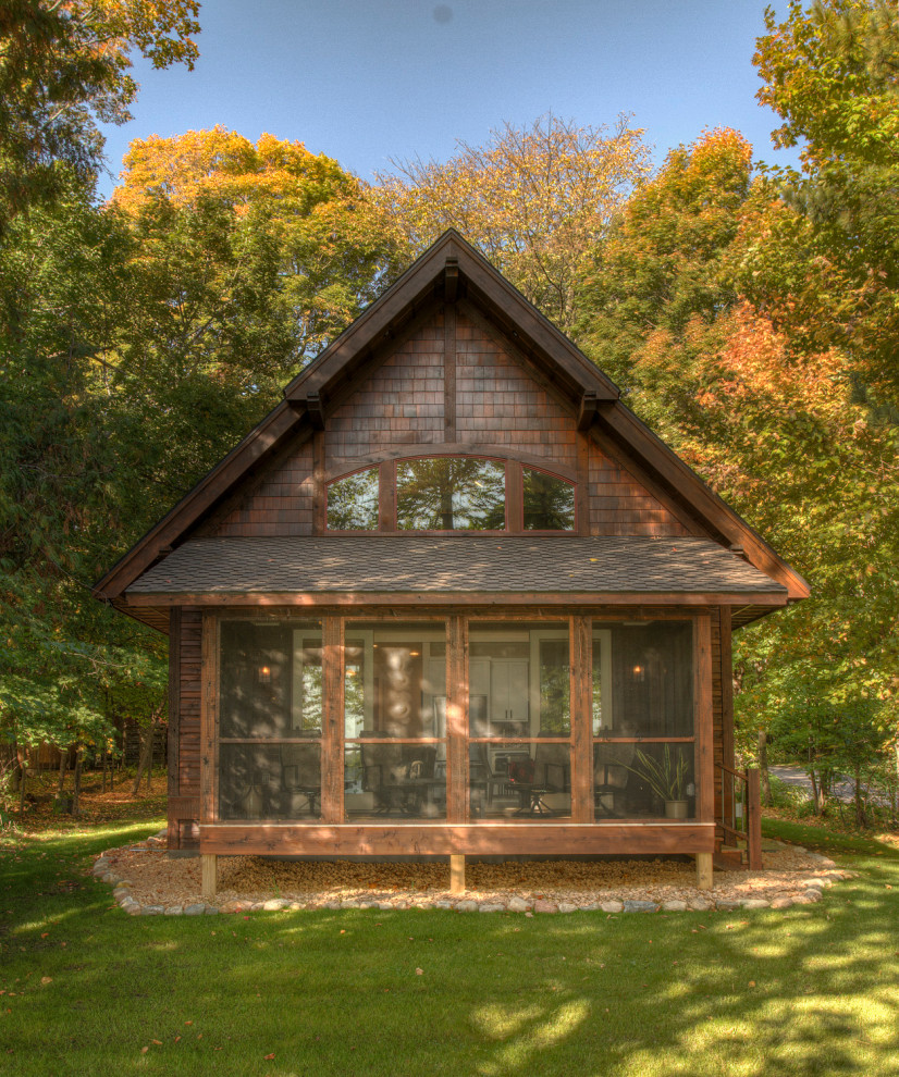На фото: маленький, двухэтажный, деревянный, коричневый частный загородный дом в стиле рустика с двускатной крышей и крышей из гибкой черепицы для на участке и в саду с