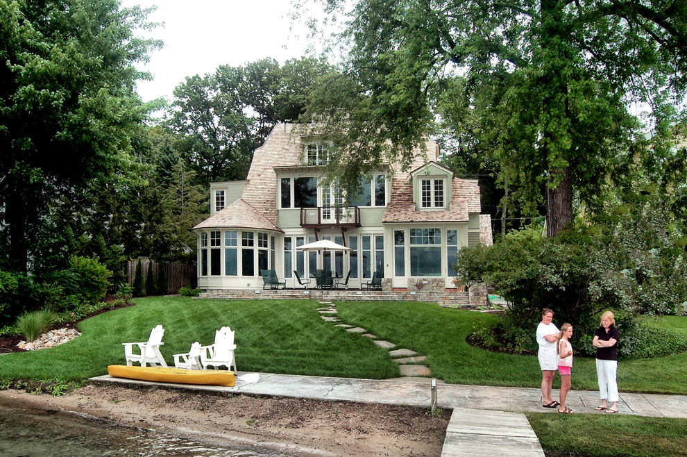 Ejemplo de fachada de casa verde tradicional grande de dos plantas con revestimiento de piedra, tejado a doble faldón y tejado de teja de madera