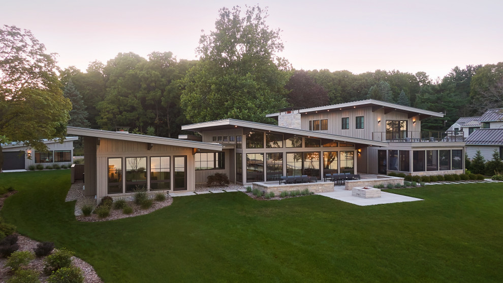 Idee per la villa ampia beige moderna a due piani con rivestimento con lastre in cemento e copertura in metallo o lamiera
