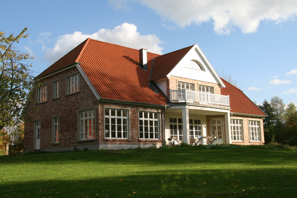 Ejemplo de fachada de casa roja campestre grande de dos plantas con revestimiento de ladrillo, tejado a la holandesa y tejado de teja de barro