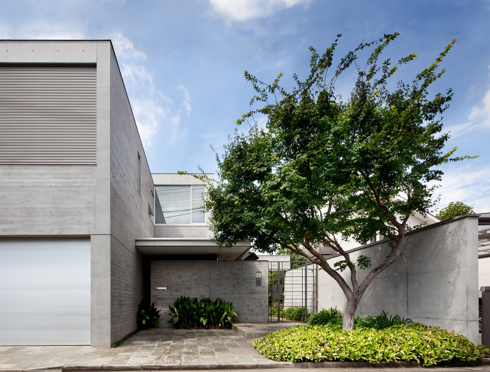 На фото: двухэтажный, серый частный загородный дом в современном стиле с облицовкой из бетона и плоской крышей с