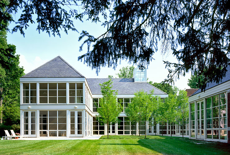 Réalisation d'une très grande façade de maison rouge minimaliste en brique à un étage avec un toit à quatre pans.